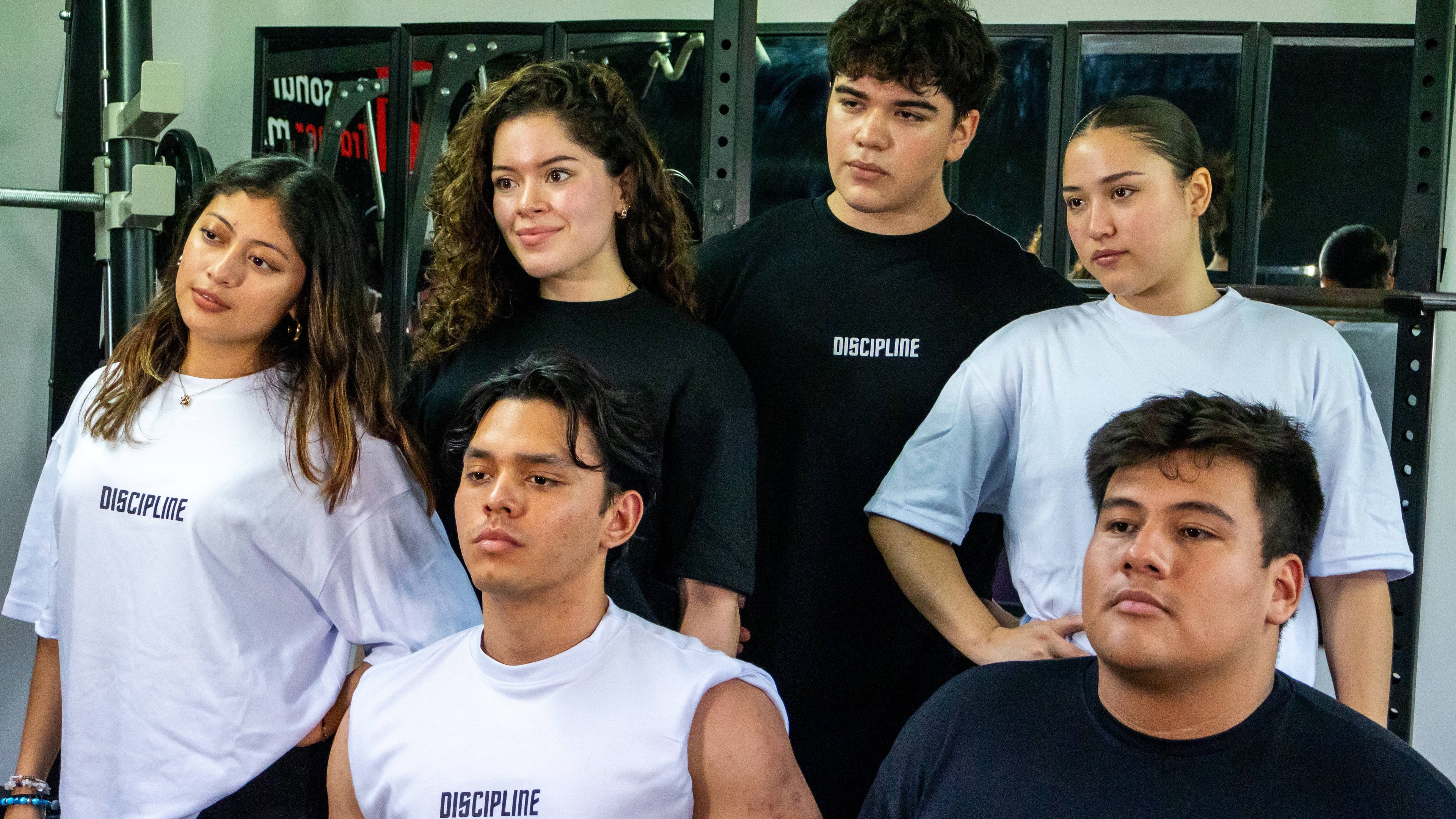 Group of people wearing 'Discipline' t-shirts in a gym setting